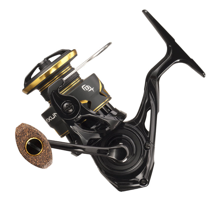 A black and gold fishing reel with a cork handle, featuring a modern design and sleek curves. The reel has metallic accents and visible branding on its body.