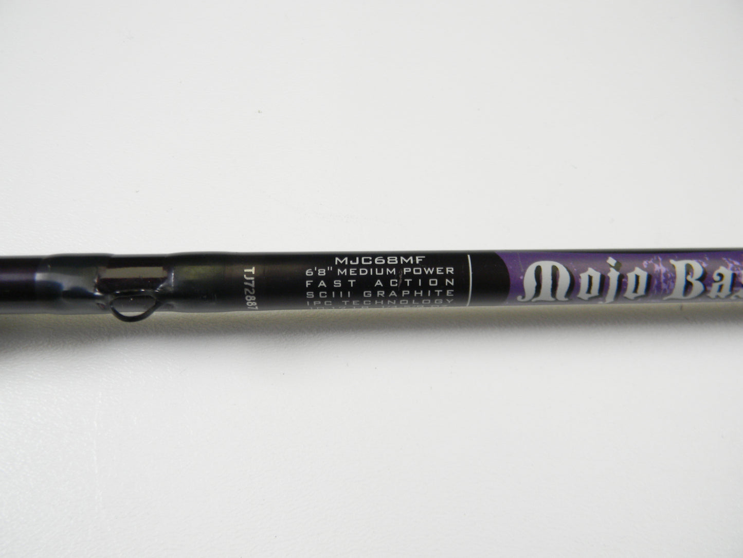Close-up of the predominantly black St. Croix Mojo Bass Jerkbait 6'8" medium power casting rod, with purple accents and SCIII graphite featuring IPC technology, ideal for our trade-in program or earning store credit.