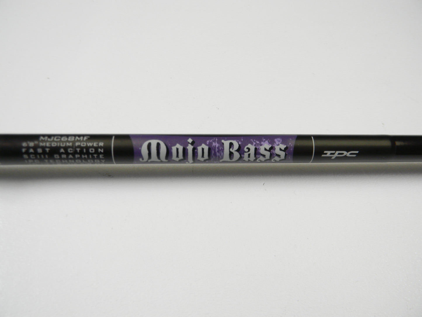 Close-up of the St. Croix Mojo Bass MJC68MF Jerkbait Casting Rod, featuring medium power, fast action, and SCIII graphite. This sleek black 6'8" rod with purple accents is part of our exclusive collection and in very good used condition.