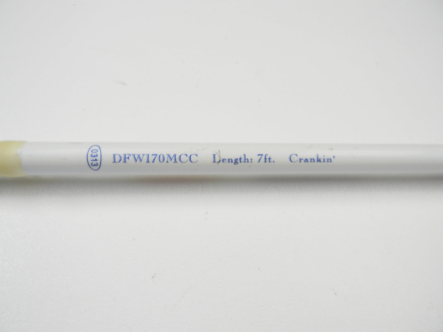 Close-up of a white Duckett rod with blue text: "DFWI70MCC Length: 7ft. Crankin'.” The used casting rod, eligible for our Rod and Reel Trade-In Program, sits on a plain white surface.
