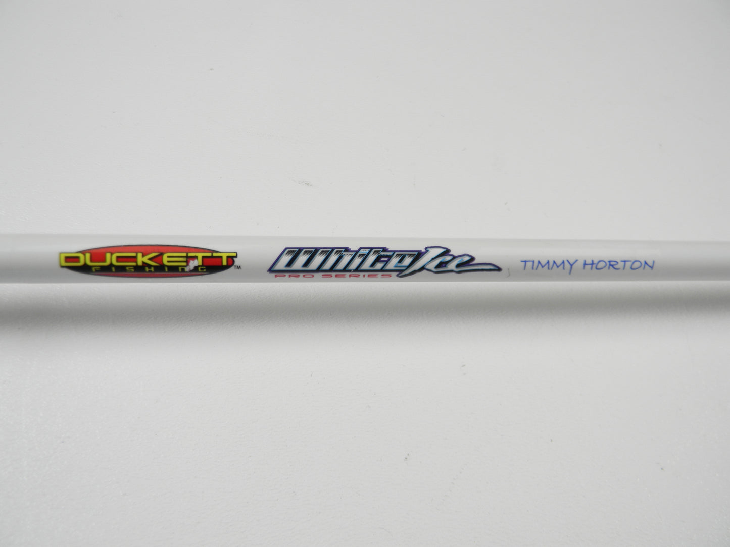 Close-up of a white Duckett casting rod with "White Ice Pro Series" and "Timmy Horton" in blue, displayed on a plain white surface, ideal for showcasing or trading through our Rod and Reel Trade-In Program to earn store credit.