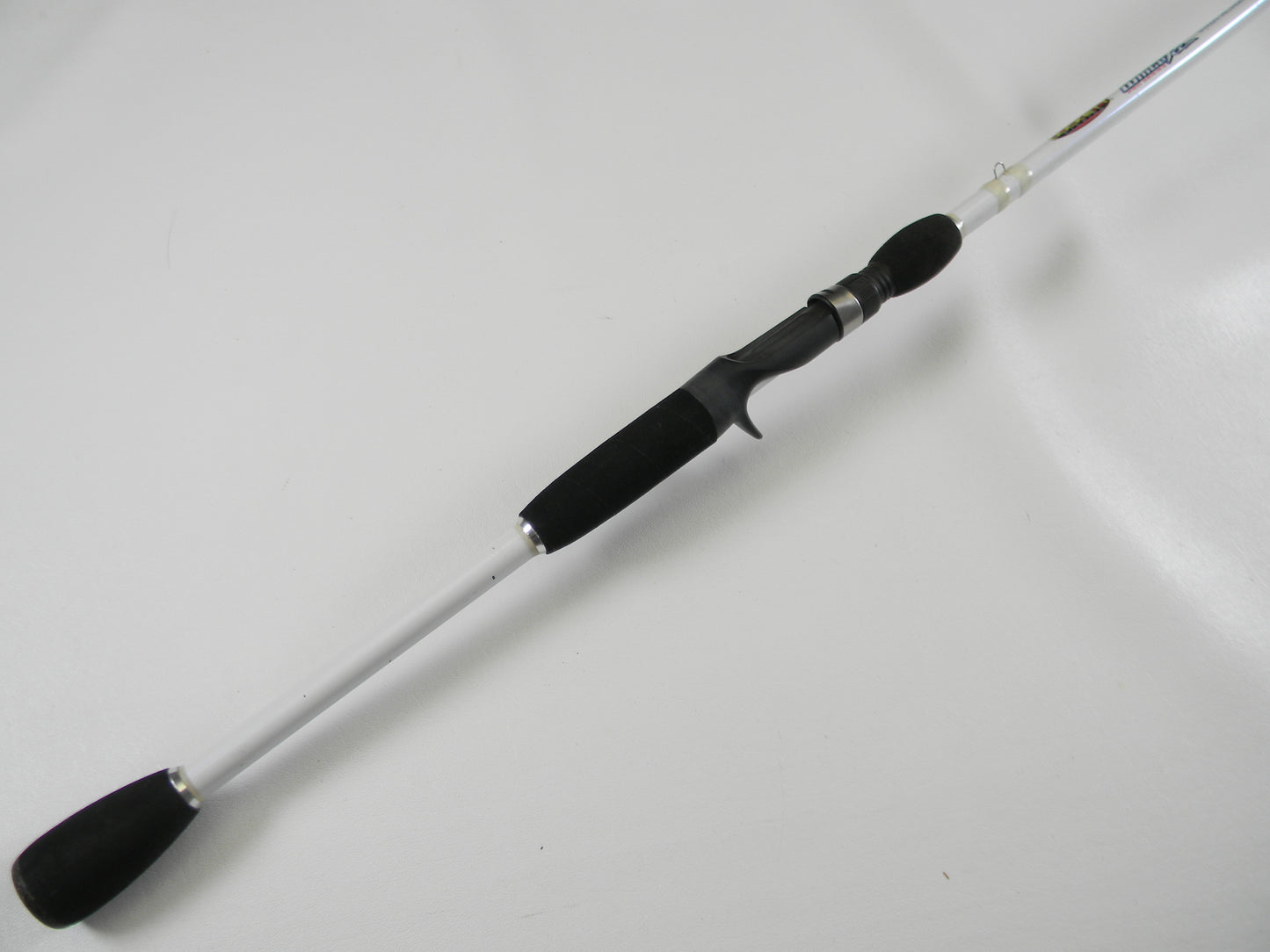 Laid diagonally on a white background, the Duckett White Ice DFWI711HC Byron Velvick 7'11" Heavy A-Rig/Swimbait used casting rod features a black handle and silver shaft. Enjoy its secure grip and metallic accents for your next catch. Trade it in through our Rod and Reel Trade-In Program for store credit.