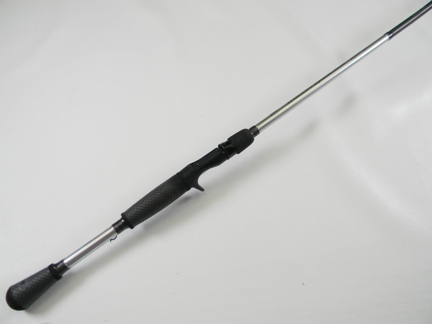 A Lew's Signature Series TLS73H Frog 7'3" Heavy casting rod, featuring a textured black grip and metallic shaft, lies diagonally against a white background. In excellent used condition, it's ideal for Rod and Reel Trade-In or those seeking exceptional quality used gear.