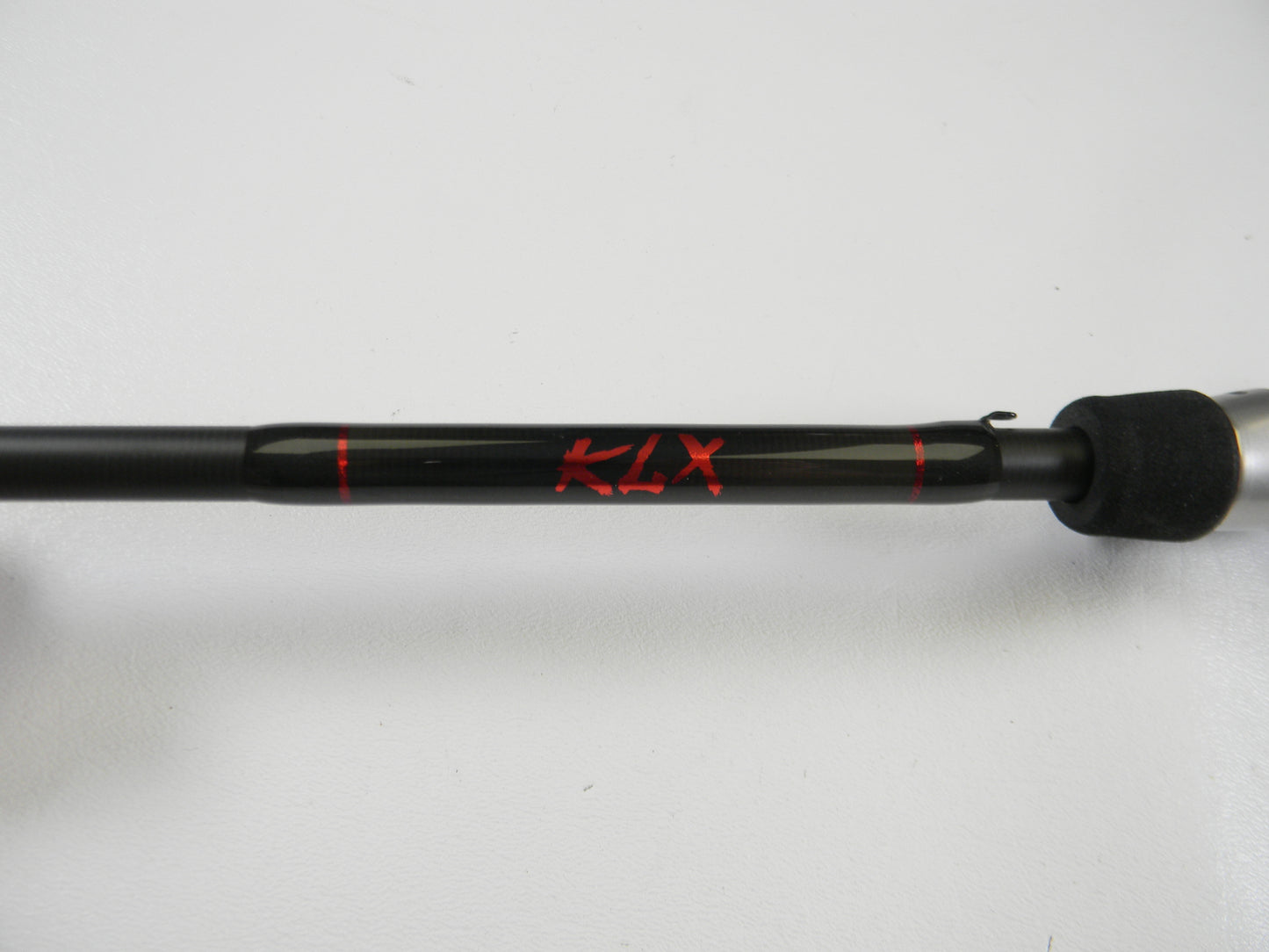 A black Kislter KLX 7'0" Medium Heavy casting rod with "KLX" in red and a textured grip is set against a white backdrop. Ideal for our Rod and Reel Trade-In Program—trade your used gear for store credit.