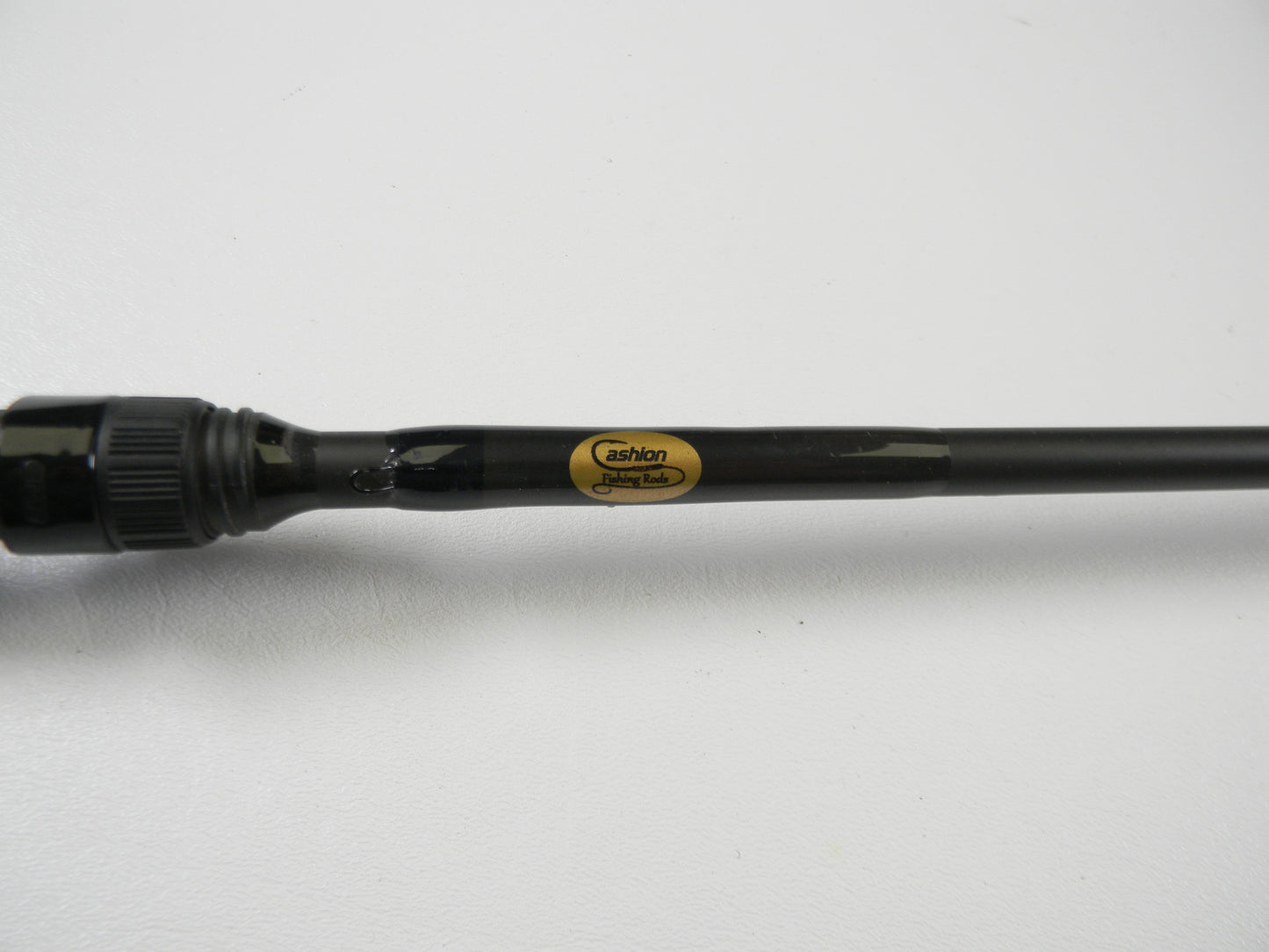 Close-up of a black fishing rod with a glossy finish, labeled "Cashion" in gold and black. Ideal for trading in used gear at select stores for credit. The sleek Cashion P84469b 6'9" Medium Heavy casting rod is displayed elegantly on a white background, showcasing its good condition.