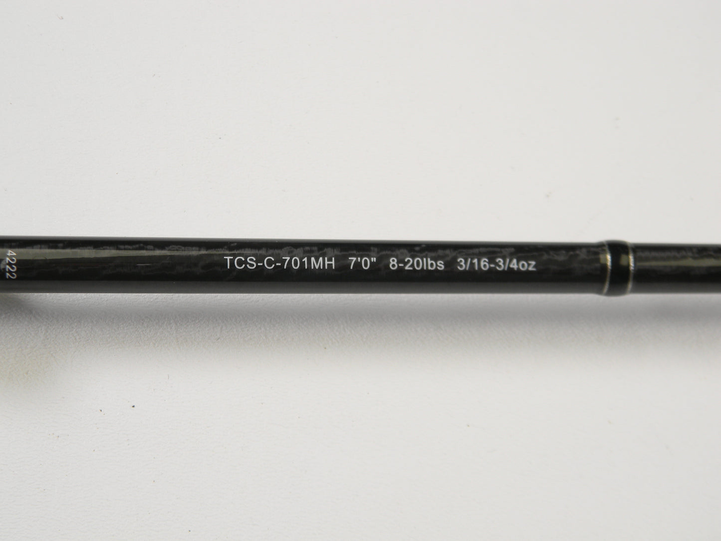 Close-up of an Okuma TCS TCS-C-701MH 7'0" Medium Heavy casting rod, showing specs "8-20lbs 3/16-3/4oz" printed in white on black. It's ideal for our Rod and Reel Trade-In Program. The rod is set against a plain white background.
