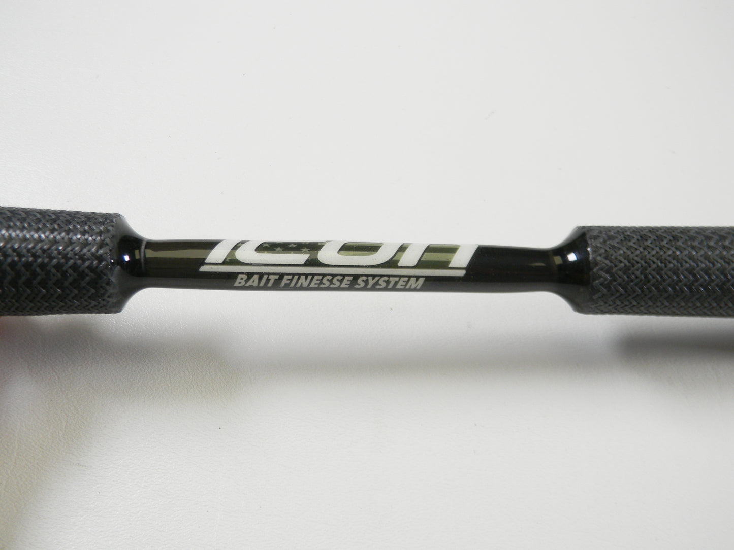 Close-up of Cashion Icon Series iBFS610MLF 6'10" Medium Light casting rod's handle with "ICON BAIT FINESSE SYSTEM" written in white. The textured dark grips are perfect for any angler considering a Rod and Reel Trade-In for store credit.
