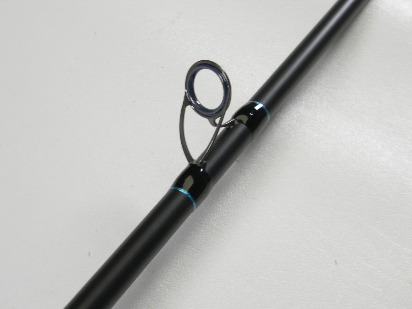 Close-up of a G. Loomis IMX-PRO Blue 845C M 7'0" Heavy Used Casting Rod in excellent condition, featuring a black finish and guide with metallic ring—ideal for those trading in gear for store credit.