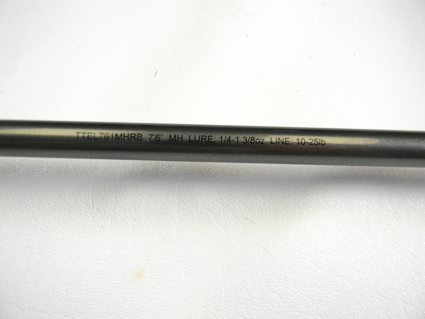 Close-up of a Daiwa Tatula Elite TTEL761MHRB rod with text: "7'6\" MH LURE 1/4-1 3/8oz LINE 10-25lb." Ideal for the Rod and Reel Trade-In Program. The rod, in mint condition, rests elegantly on a plain white surface.
