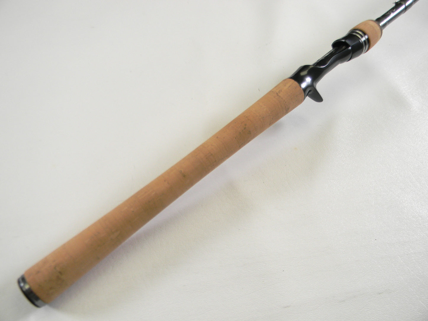 A close-up of a Daiwa Tatula Elite TTEL751MHFB fishing rod, featuring a cork handle and black reel seat, perfect for those considering our Rod and Reel Trade-In Program for store credit. Resting on a smooth white surface, it showcases quality craftsmanship in every detail.