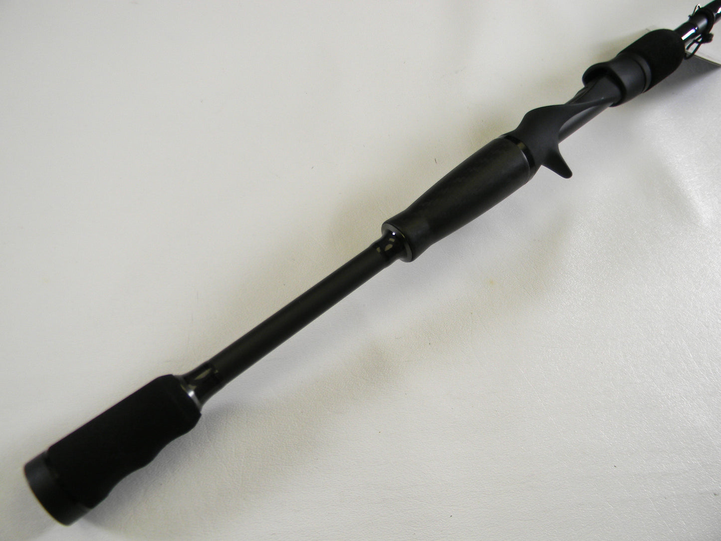 Close-up of the Abu Garcia Veritas Tournament VXTC72-5 black handle against a white background. This used casting rod features a comfortable trigger grip design. Perfect for upgrading in our Rod and Reel Trade-In program with generous store credit offers.