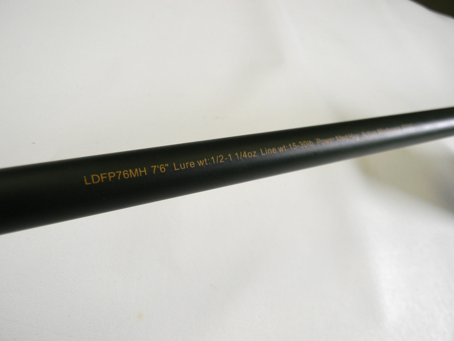 A close-up of the Lew's David Fitts Perfect Crankbait LDFP76MH 7'6" Medium Heavy rod shows text: "Lure wt: 1/2-1 1/4oz Line wt: 15-30lb." Against a plain white background, it could be perfect for your next Rod and Reel Trade-In.