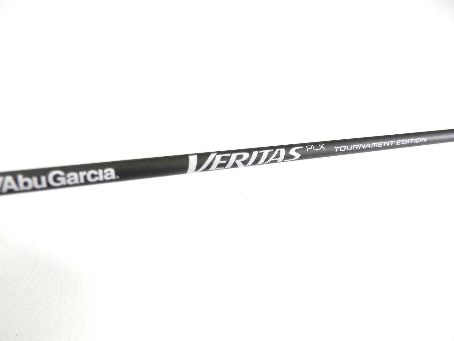 A close-up shows an Abu Garcia Veritas Tournament VXTS610-4 in mint condition with "Veritas PLX Tournament Edition" in white on a black background and "Abu Garcia" at the bottom left, set against a plain, light-colored backdrop. Ideal for this Rod and Reel Trade-In opportunity.