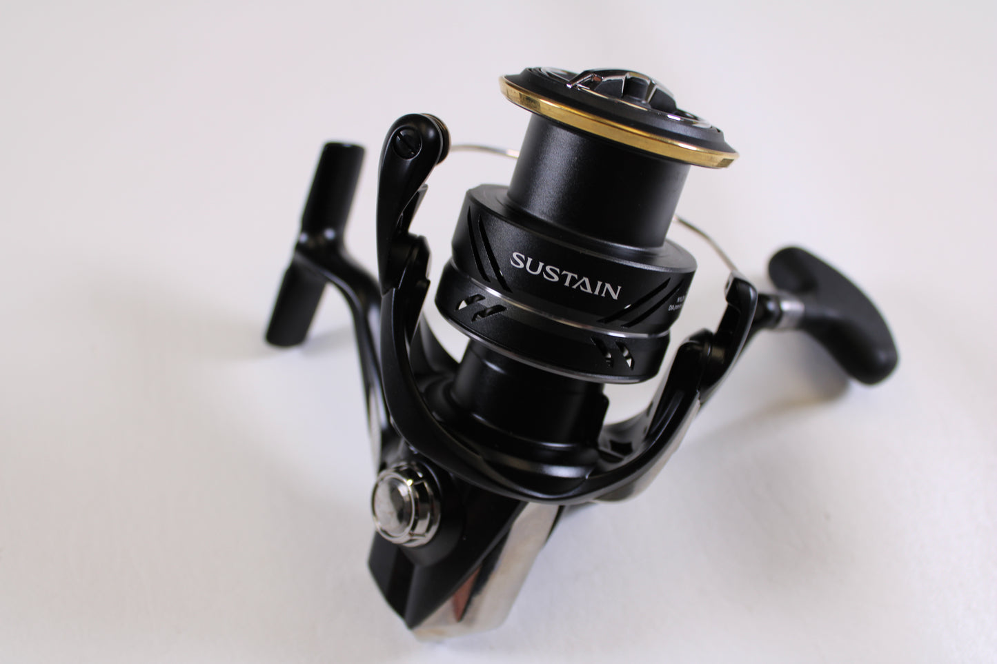 A close-up of the Shimano Sustain FJ SA4000XGFJ 6.2:1 Spinning Reel in Mint Used Condition, featuring metallic and gold accents with a visible spool and handle—perfect for Rod and Reel Trade-In or store credit.