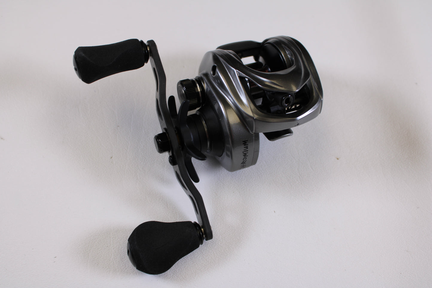 A close-up of a Kistler Chromium 7.3:1 RH—Used Casting Reel in excellent condition, featuring padded handles on a white surface—ideal for our Rod and Reel Trade-In Program to earn store credit with quality used Kistler gear.