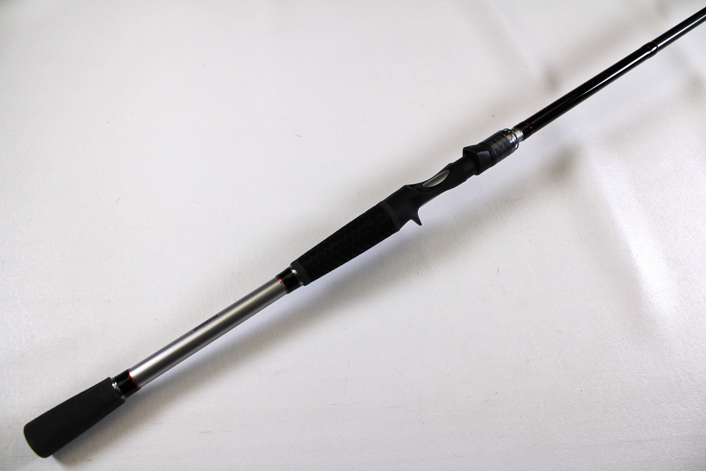 The Shimano Intenza NTZC78XH 7'8" XH Used Casting Rod, in excellent condition, is displayed diagonally on a plain white background. The rod features black and silver accents with a black grip handle.