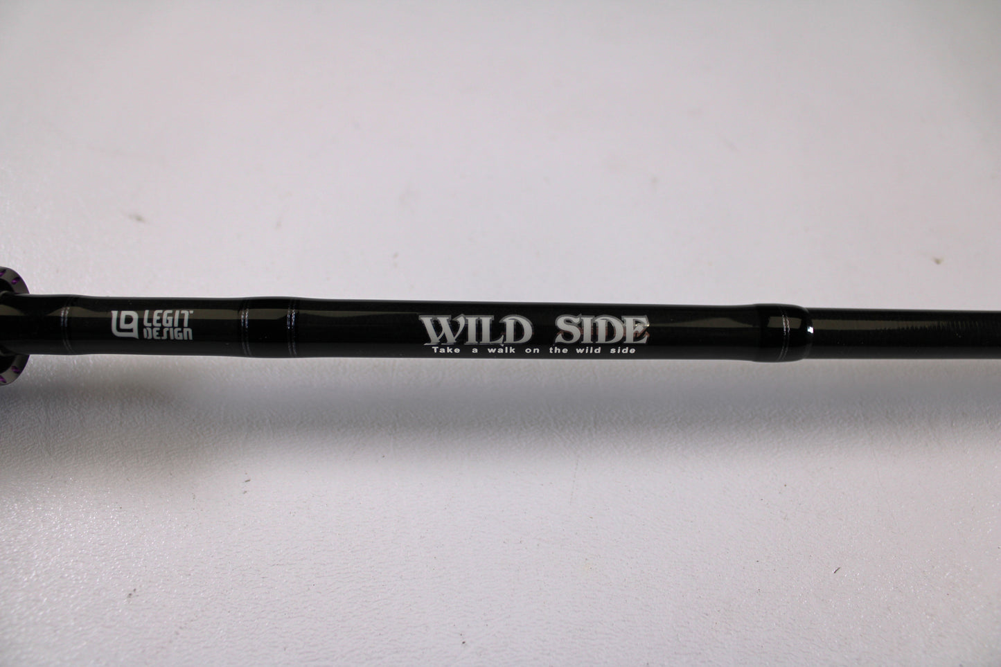 A close-up of a black Legit Design Wild Side WSC 610MH 6'10" Medium Heavy casting rod in excellent used condition, featuring white "WILD SIDE," "Take a walk on the wild side," and "LEGAL DESIGN" text. Trade in your gear for store credit.