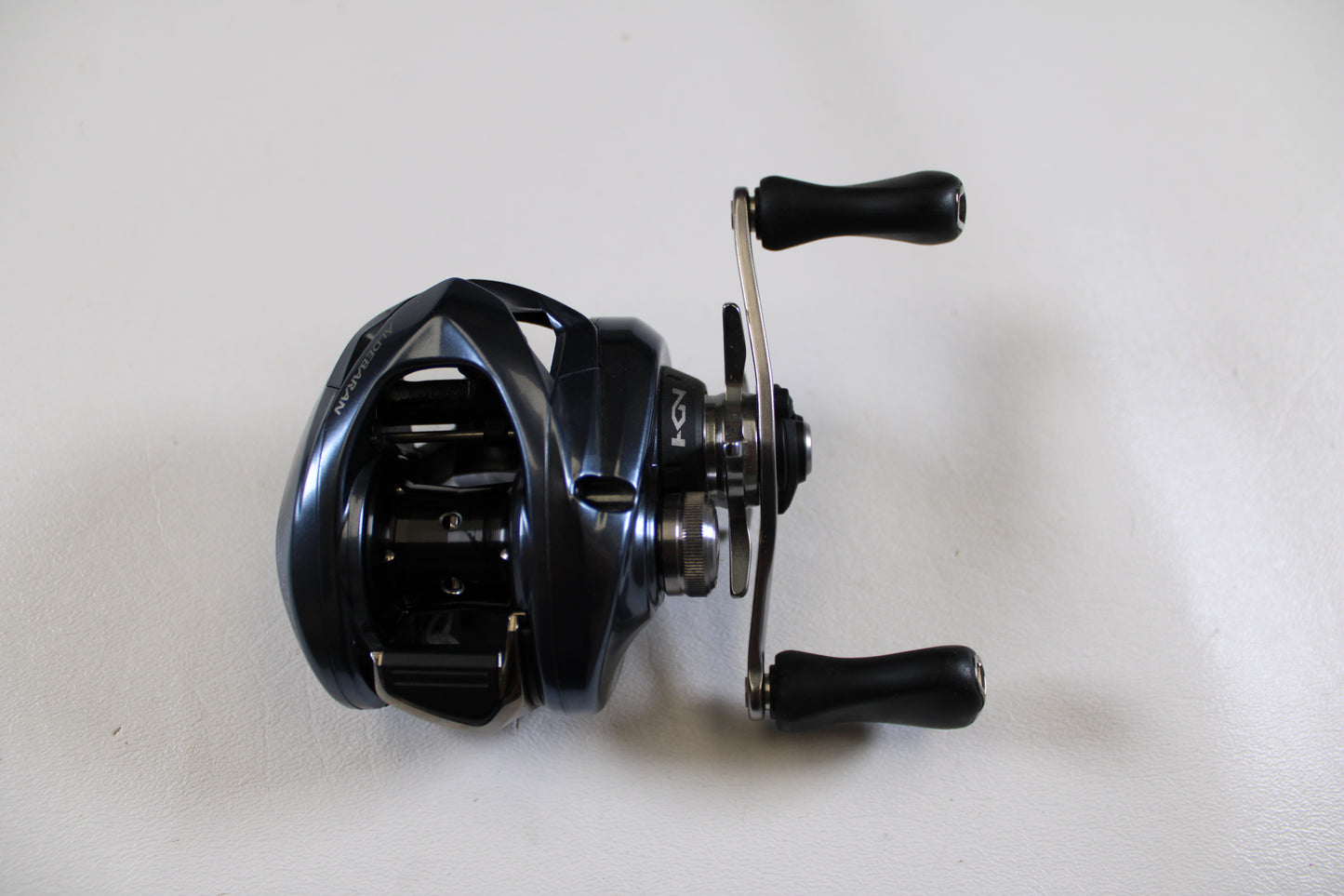 A close-up of a Shimano Aldebaran MGL ALDMGL50HG used casting reel in excellent condition, set on a white surface—ideal for upgrading with our Rod and Reel Trade-In or buying quality Shimano gear with store credit.