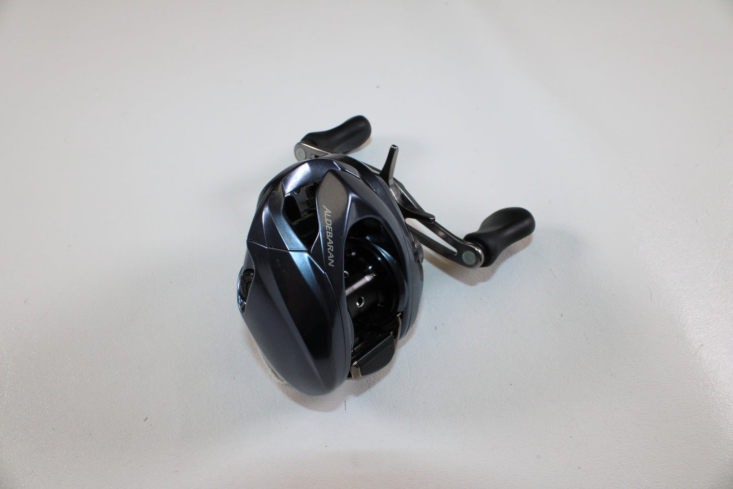 A Shimano Aldebaran MGL ALDMGL50HG casting reel in excellent used condition rests on a white surface—ideal for upgrading via our Rod and Reel Trade-In program or earning store credit for your used Shimano gear.