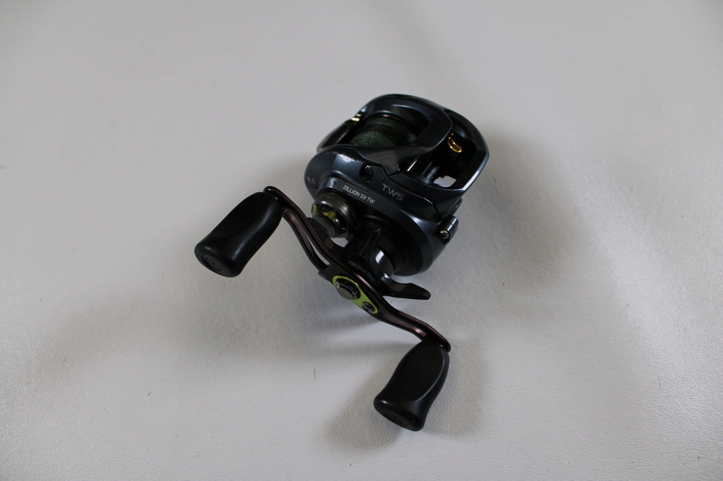 A used Daiwa Zillion SV TW JDM casting reel (9.1:1 gear ratio, black/metallic, two handles) in good condition is displayed on a plain white surface.
