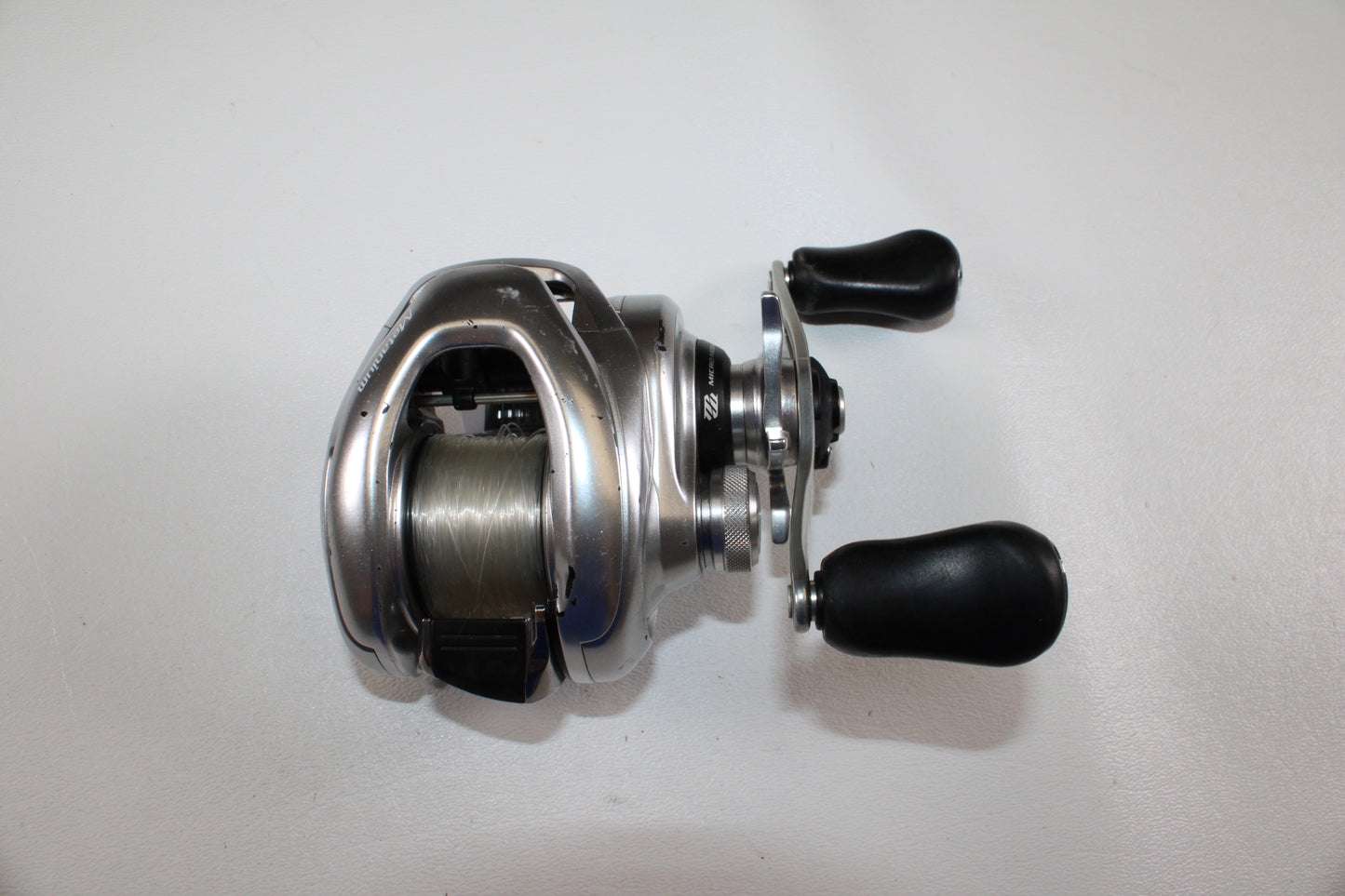 The Shimano Metanium MGL 150 XG 8.5:1 Used Casting Reel (Good Condition) is a quality silver baitcasting reel with two black handles—ideal for anglers shopping our Rod and Reel Trade-In Program for trusted Shimano gear.