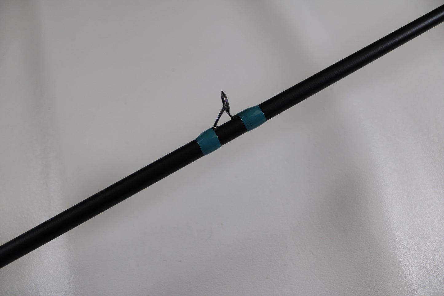 A close-up of the G. Loomis NRX+ 904C MBR Used Casting Rod in excellent condition, featuring two blue bands and a metal line guide—part of the Nation's Best Rod collection and eligible for our Rod and Reel Trade-In Program.