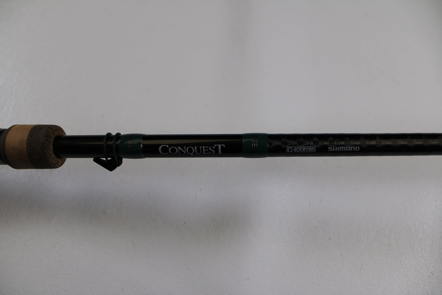 Close-up of the G. Loomis Conquest CNQ 905C MBR Used Casting Rod in very good condition, showing "CONQUEST" and "G.Loomis" logos on the black shaft with cork handle—ideal for our Rod and Reel Trade-In Program or for store credit.