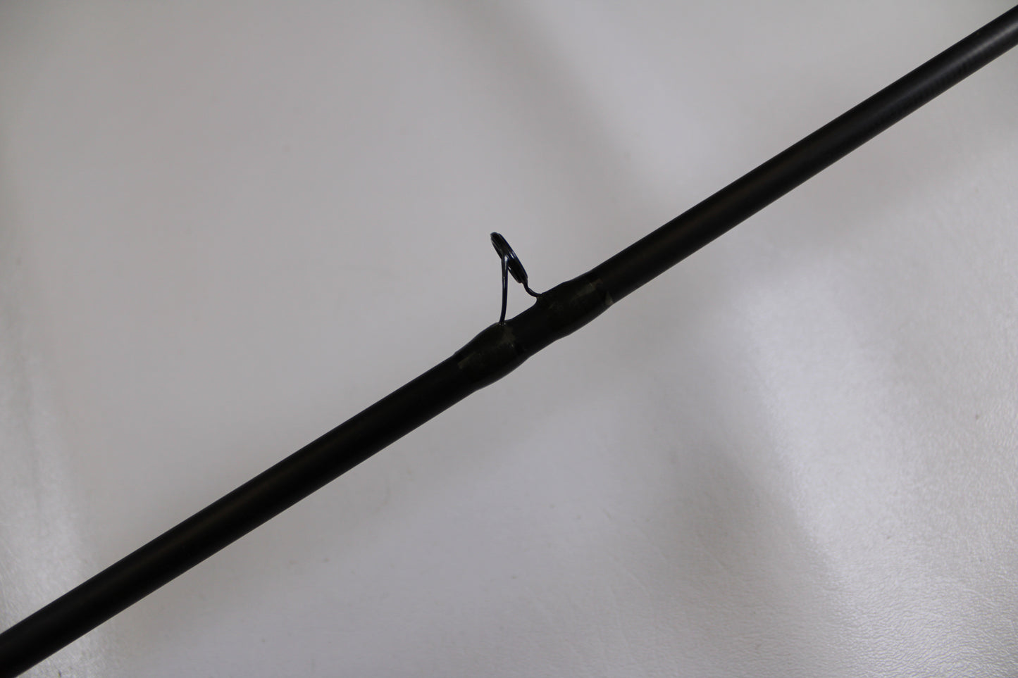 A close-up of the G. Loomis MBR844c IMX 7'0" Heavy - Used Casting Rod (Good Condition) highlights one of its guides against a plain white background.