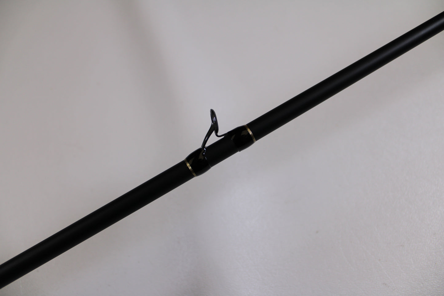 A close-up of the G. Loomis GLX 893c JWR 7'5" Medium Heavy Used Casting Rod in excellent condition shows a line guide wrapped with gold and black thread—ideal for those interested in used gear or our Rod and Reel Trade-In for store credit.