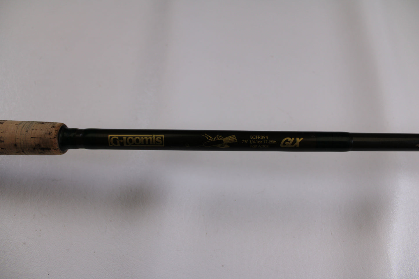 Close-up of the G. Loomis BCFR894 GLX used casting rod in good condition, featuring gold model details on a dark shaft with cork grip—ideal for upgrading your gear through our rod and reel trade-in program for store credit.