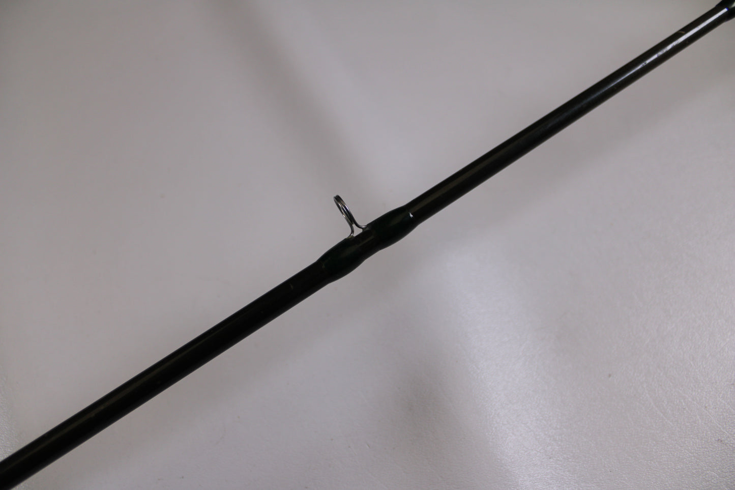 A close-up of the G. Loomis BCFR894 GLX, a used casting rod in good condition, features a single metal line guide against a plain white background—ideal for anglers interested in our rod and reel trade-in program.