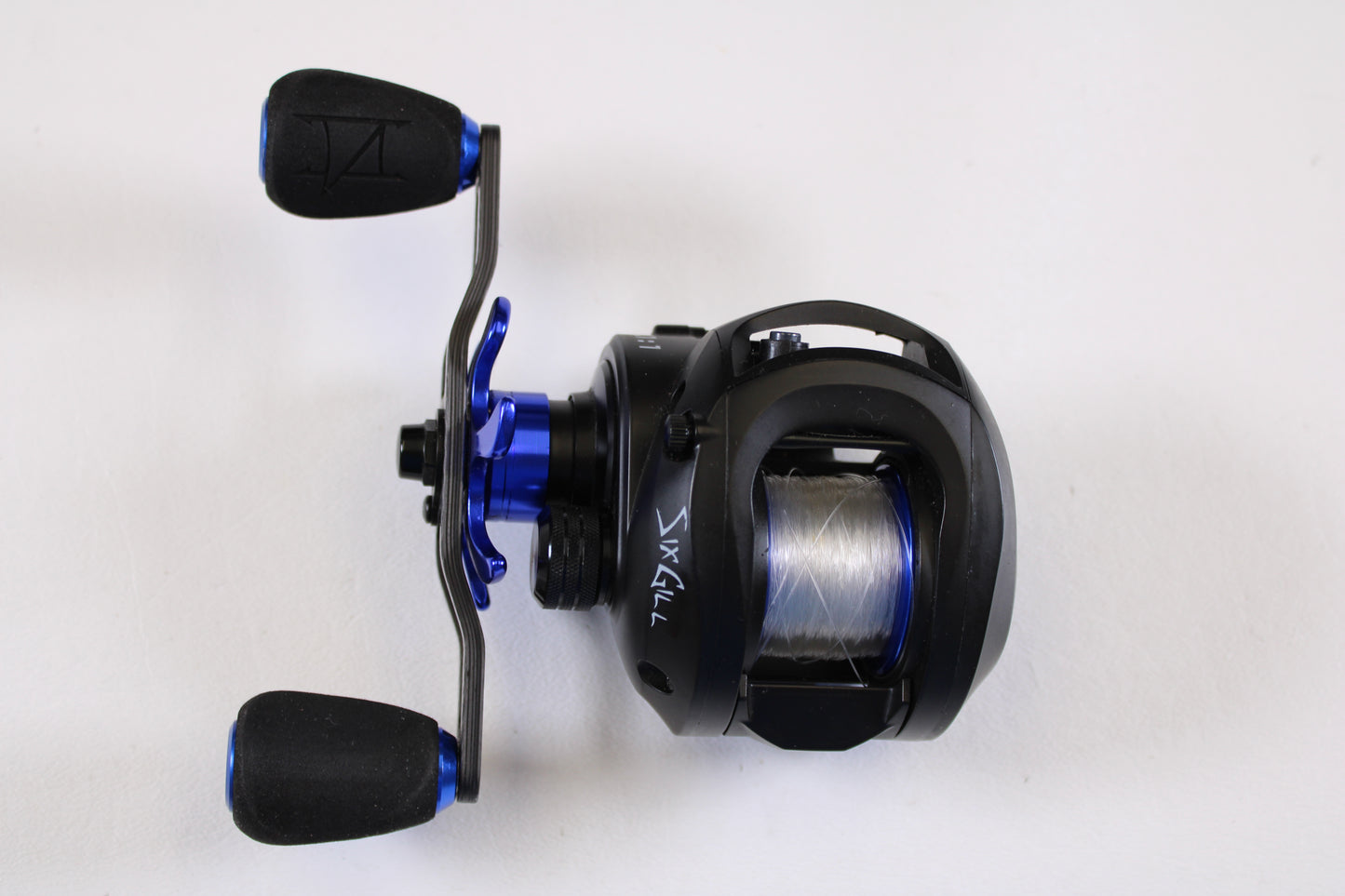 The SixGill Crius 7.1:1 LH Used Casting Reel (Excellent Condition) by SixGill, featuring a black and blue design with a handle, two grips, and clear line, is shown on a white background—ideal for rod and reel trade-in store credit.