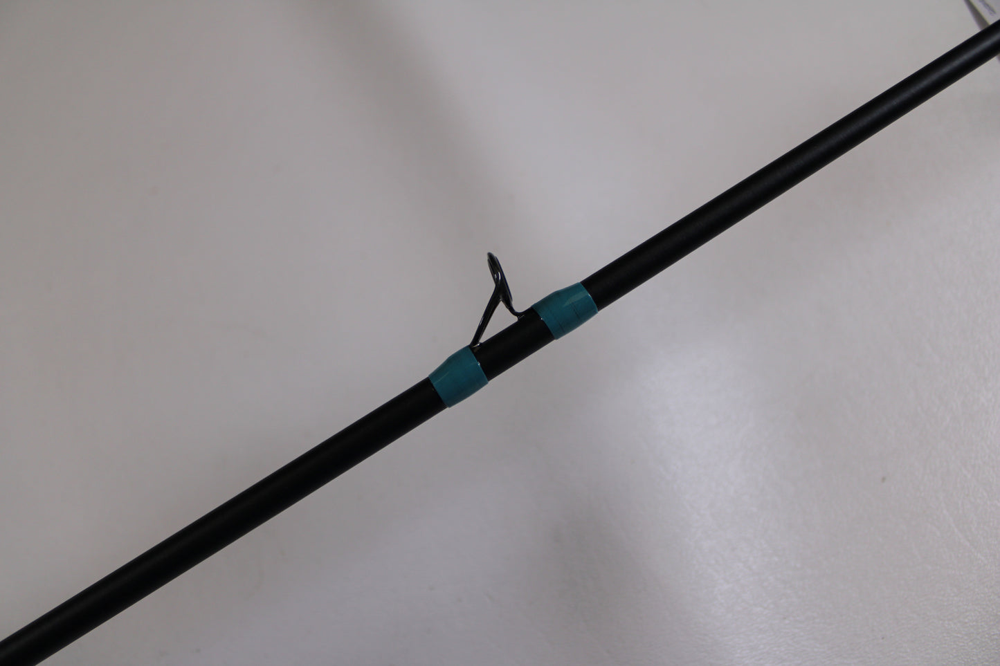 A close-up of the G. Loomis NRX+ 781c Inshore 6'6" Med-Lite Used Casting Rod in excellent condition, featuring a metal guide ring and teal thread wraps—ideal for our Rod and Reel Trade-In Program or upgrading your gear.