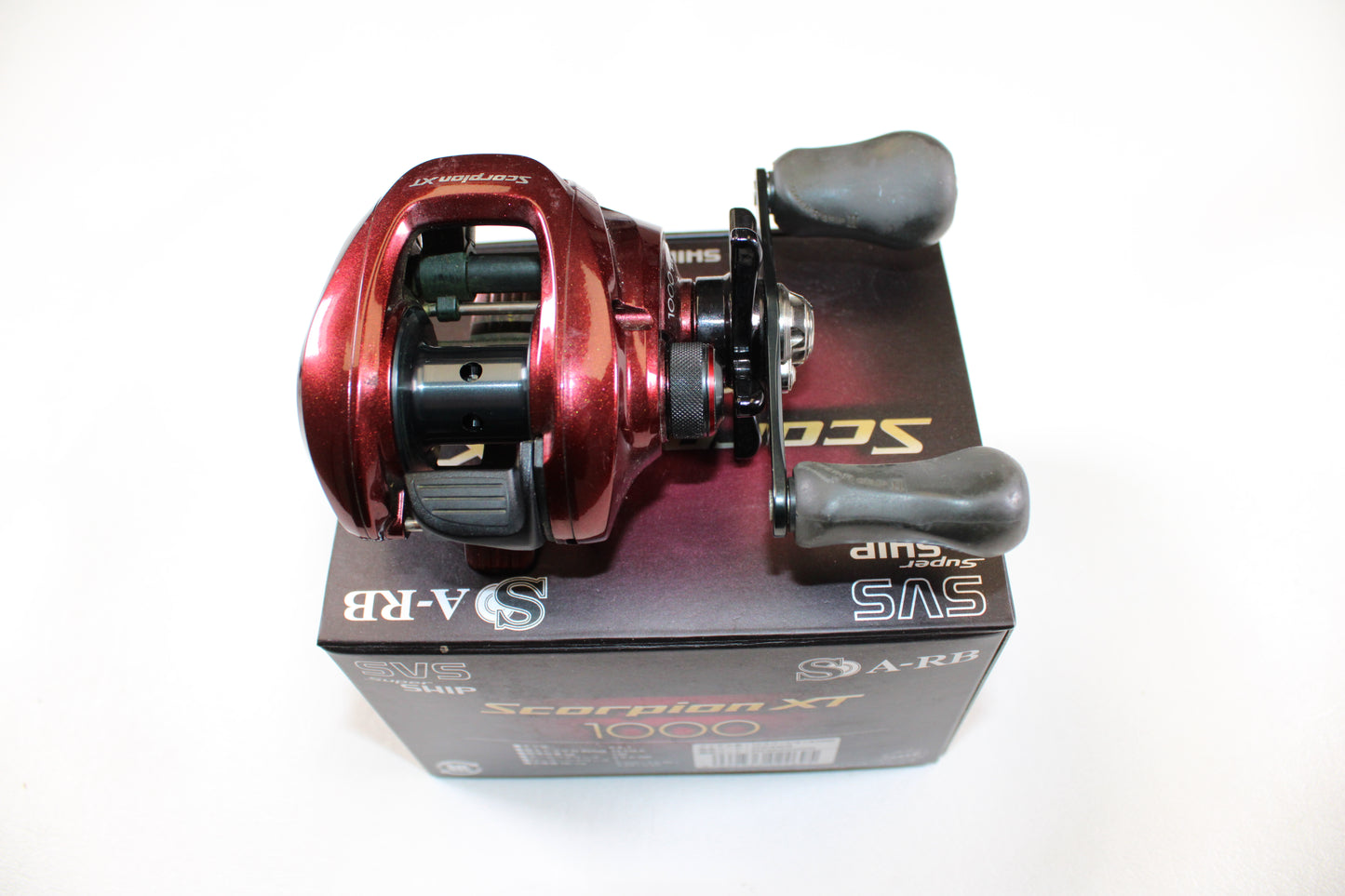 A Shimano Scorpion XT 1000 6.4:1 Used Casting Reel in Very Good Condition is displayed on its branded box—trade in your gear with our Rod and Reel Trade-In Program to earn store credit.