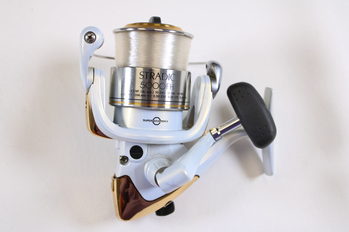 Shimano Stradic 5000FH Used Spinning Reel in very good condition, silver and white with black handle and gold accents. Photo on white background. Eligible for our rod and reel trade-in program when you upgrade or exchange used gear.