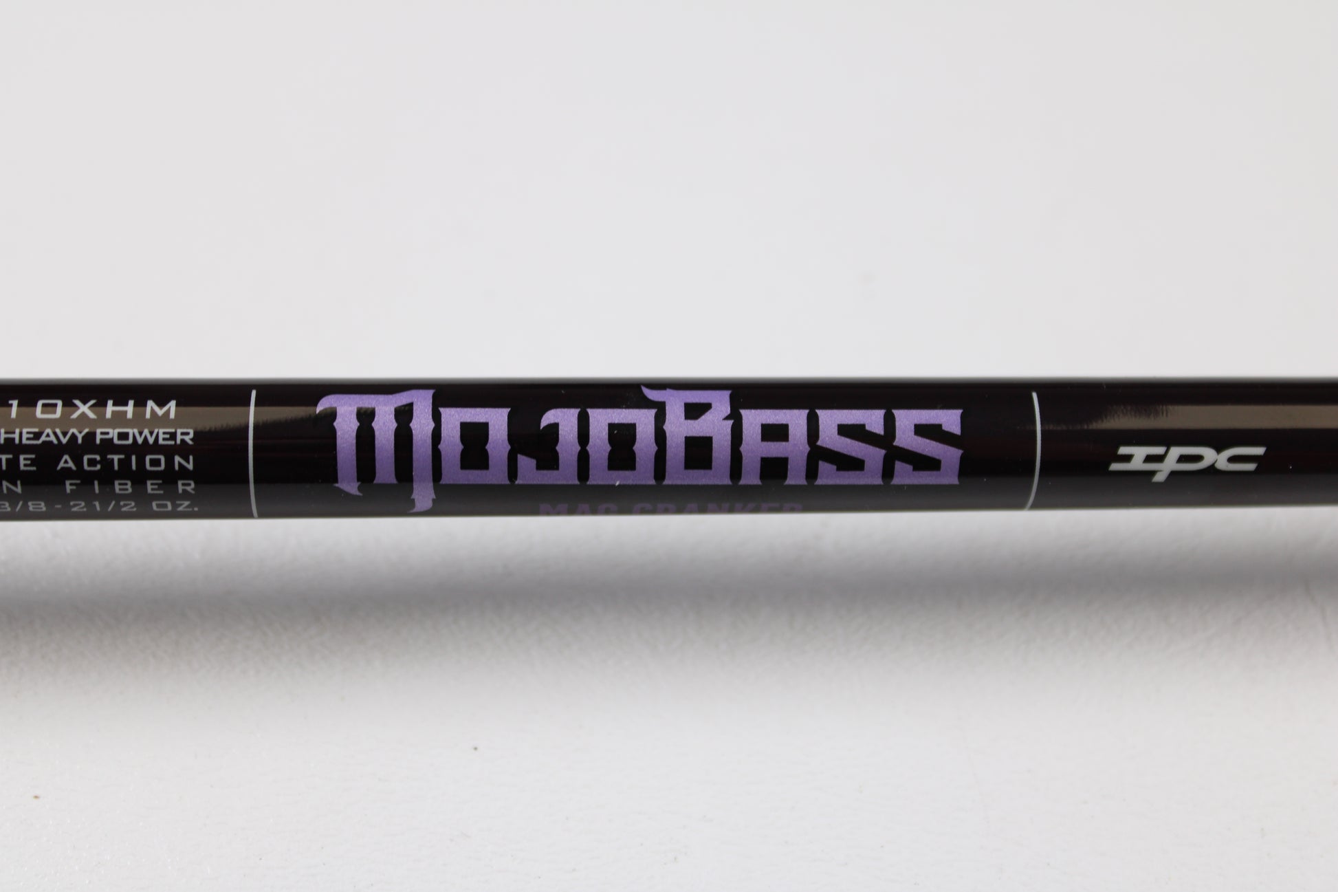 Close-up of a black St. Croix Mojo Bass JOC710XHM Mag Cranker 7'10" XH used casting rod in mint condition, featuring purple "Mojo Bass" text and symbols on white background. Trade in your gear for store credit through our Rod and Reel Trade-In Program.