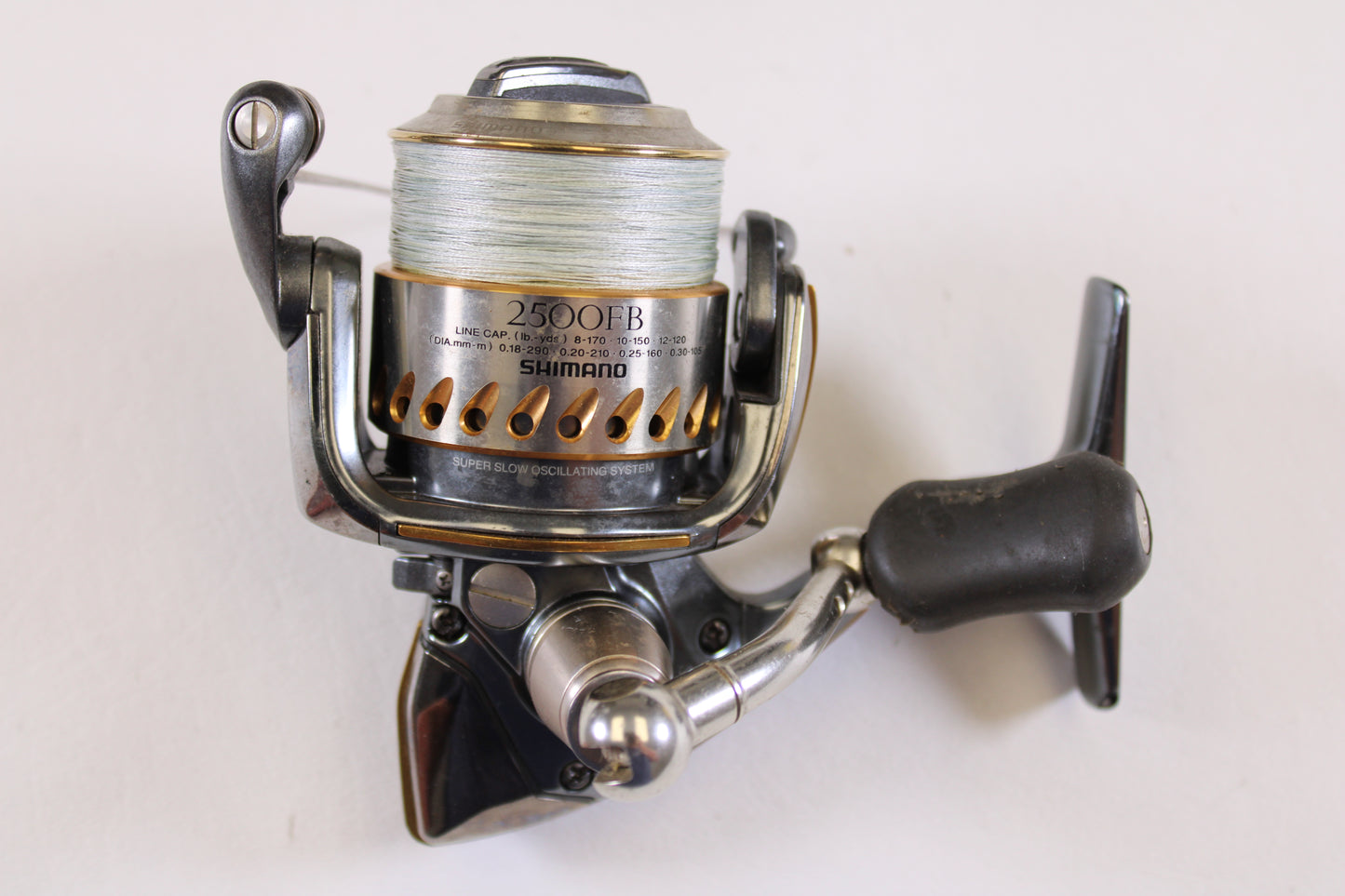 A close-up of a Shimano Stella FB 2500FB used spinning reel in very good condition with fishing line on the spool, set against a white background—ideal for those seeking quality pre-owned Shimano gear.