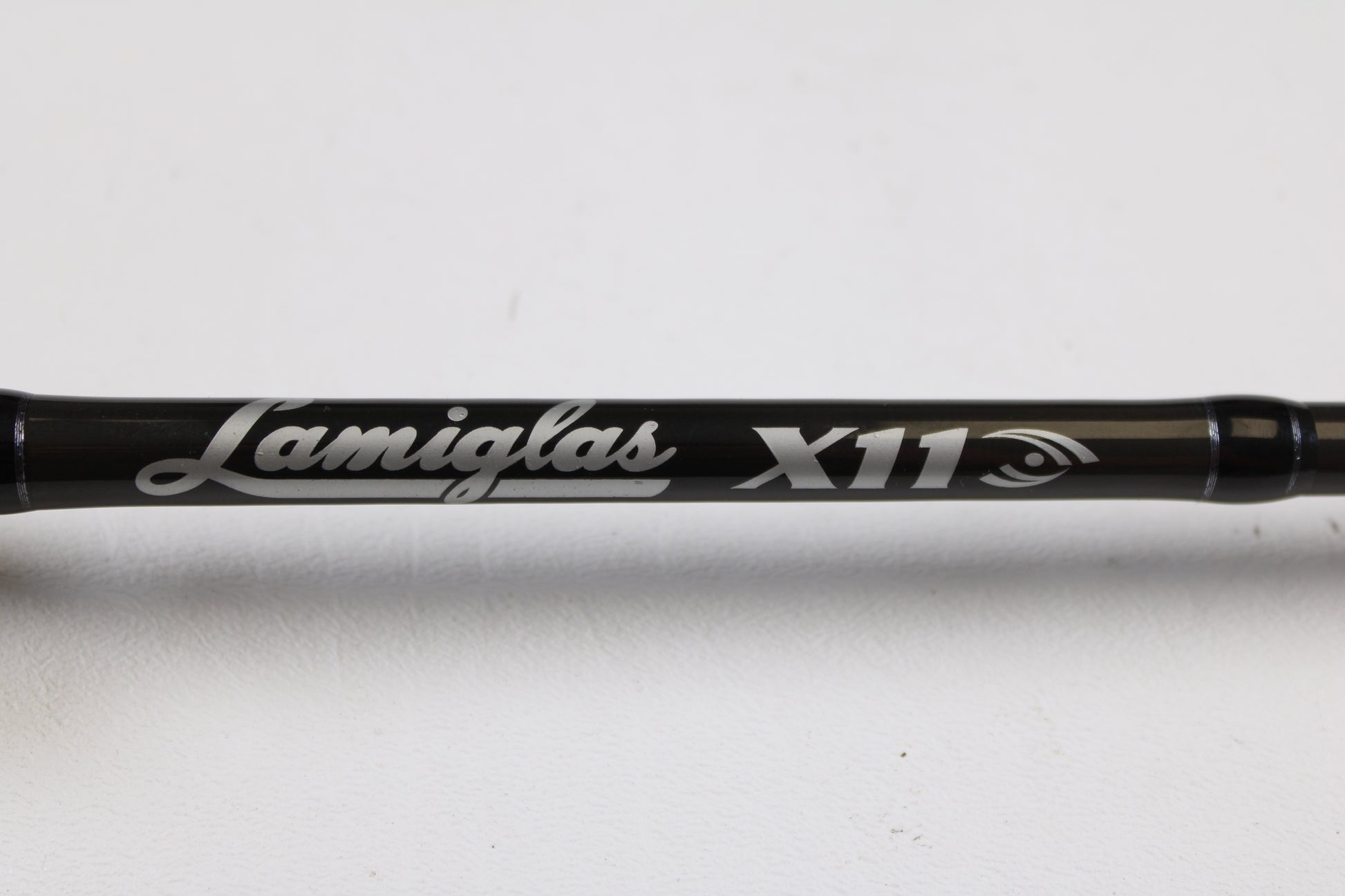 A close-up of a Lamiglas X11 Graphite Handle LX86MCGH 8'6" Medium 2 Piece Used Casting Rod in excellent condition, featuring the Lamiglas brand and model name in white lettering, displayed against a plain white background.