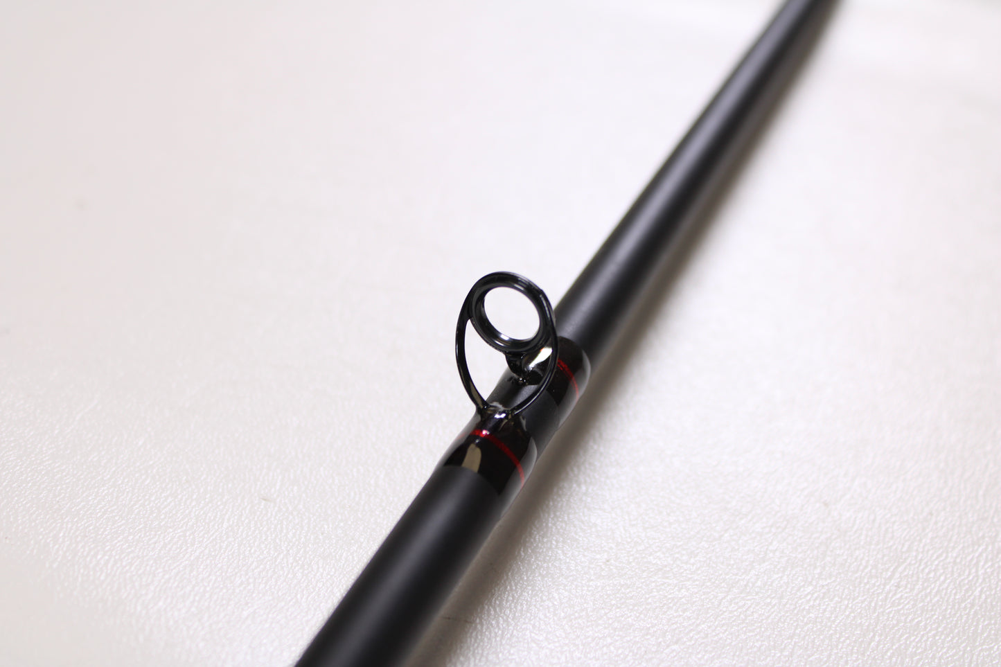A close-up of the G. Loomis Salmon & Steelhead IMX 1084-2C SATR 9'0" Used Casting Rod in excellent condition, featuring a metal guide ring, is shown against a plain white background.