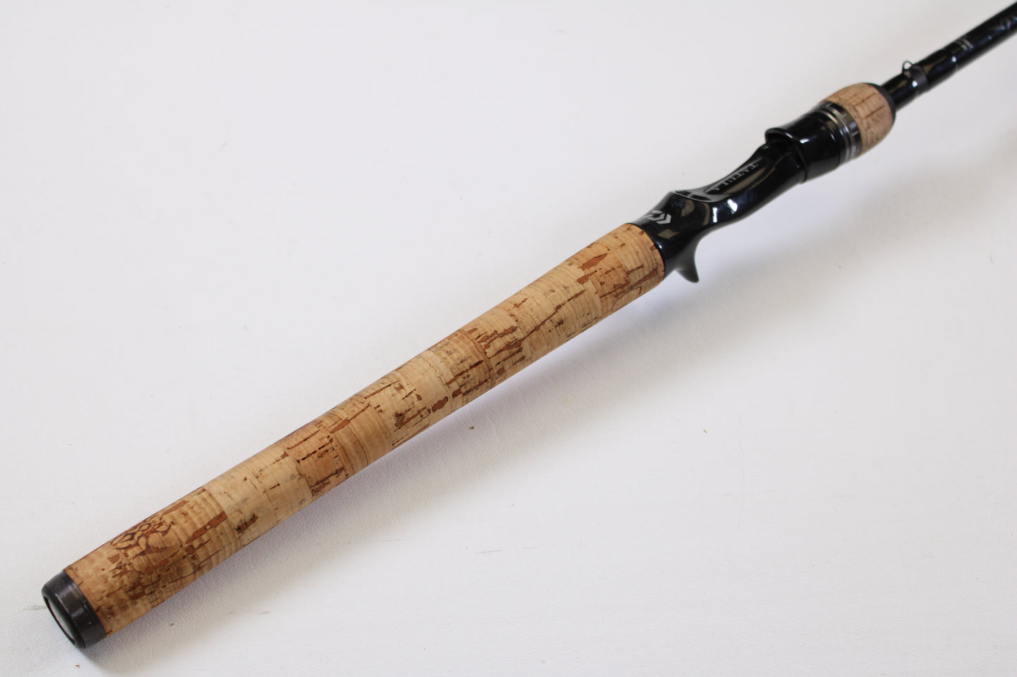 A close-up of the Daiwa Tatula TTU741HRB-G 7'4" Heavy Glass rod's cork handle and black reel seat, shown on a white background—ideal for those looking to upgrade through our Rod and Reel Trade-In Program.