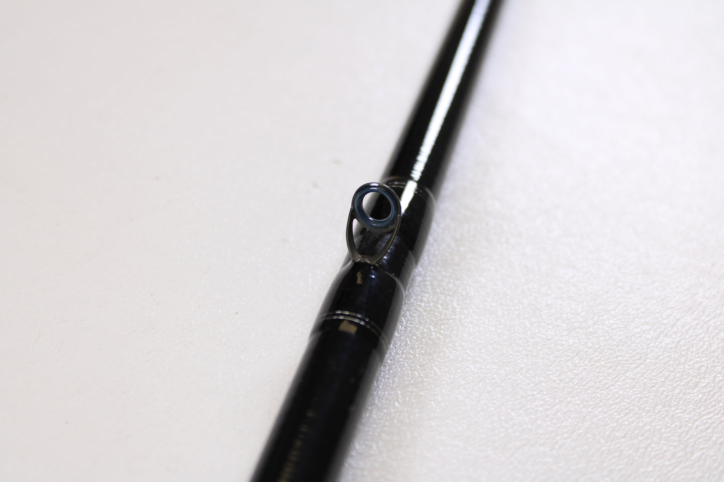 Close-up of a Daiwa Tatula TTU741HRB-G 7'4" Heavy Glass used casting rod in very good condition, featuring a single guide ring on a white surface—perfect for those interested in quality used gear or our Rod and Reel Trade-In Program.