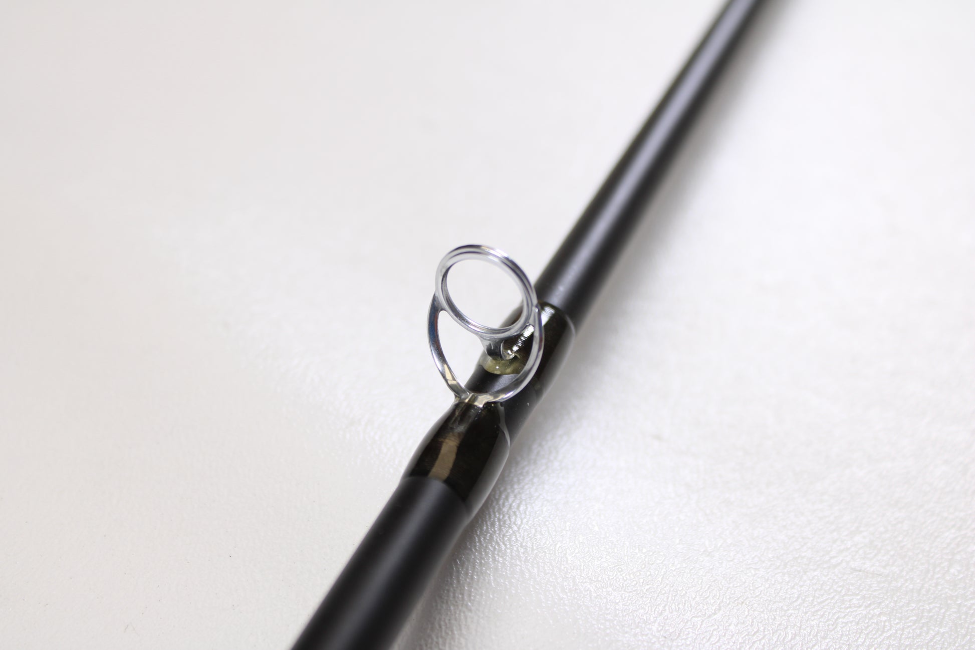 Close-up of a Temple Fork TFO Tactical Bass TACMBR734-1 7'3" Medium Used Casting Rod in excellent condition, showing the shiny metal guide on a black rod—ideal for those considering our rod and reel trade-in program.