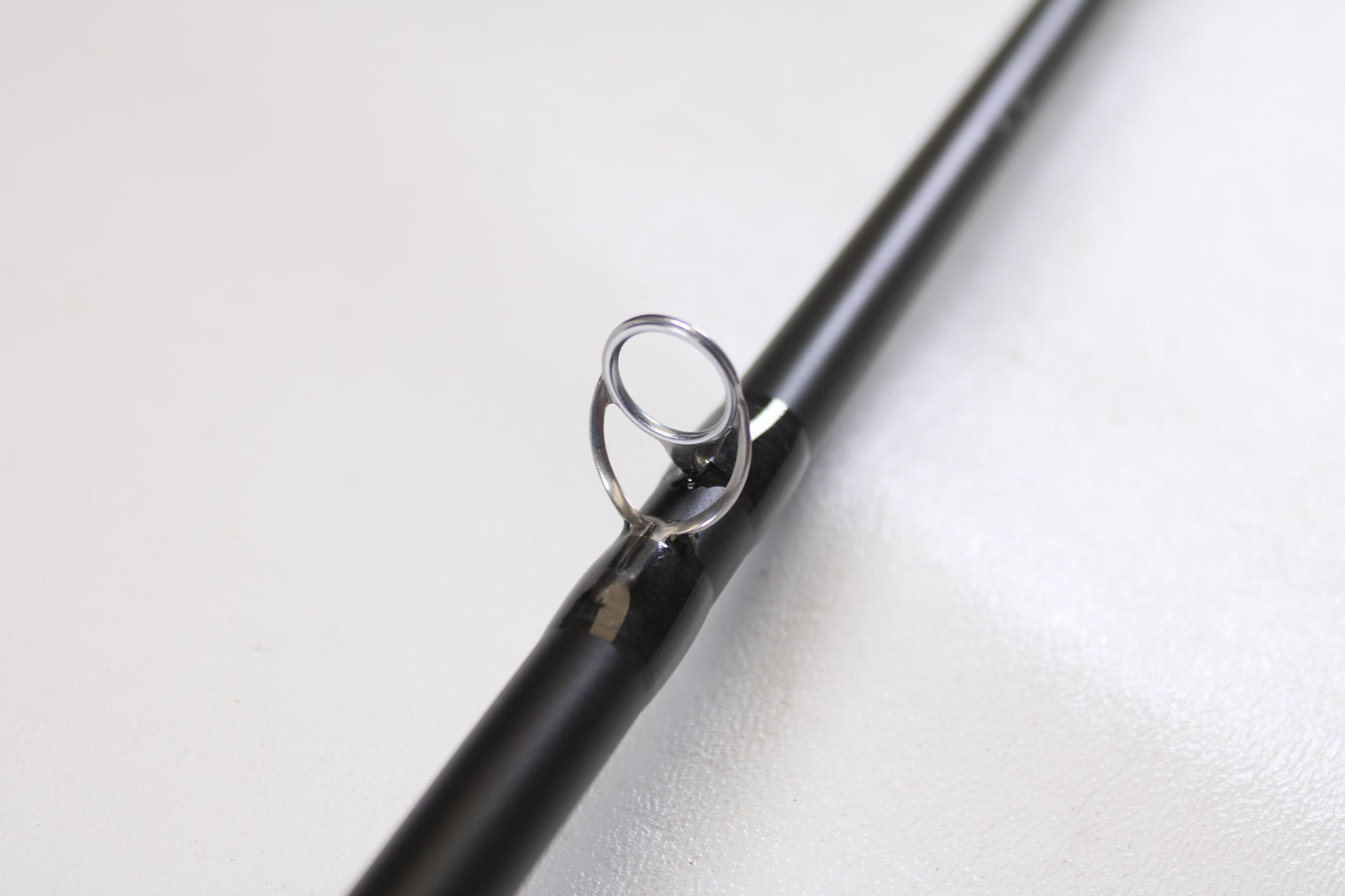 Close-up of a Temple Fork TFO Tactical Bass TACSB726-1 7'2" Heavy used casting rod in excellent condition, highlighting the metal guide ring—perfect for anglers interested in quality pre-owned gear or our trade-in program.