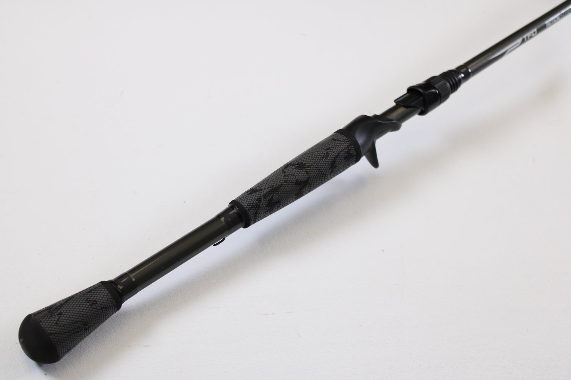 A close-up of the Temple Fork TFO Tactical Elite Bass TLE SC 747-1 7'4" Ex-Heavy casting rod handle—black with a textured grip and trigger reel seat—shows this quality used gear, ideal for anglers trading in rods and reels.