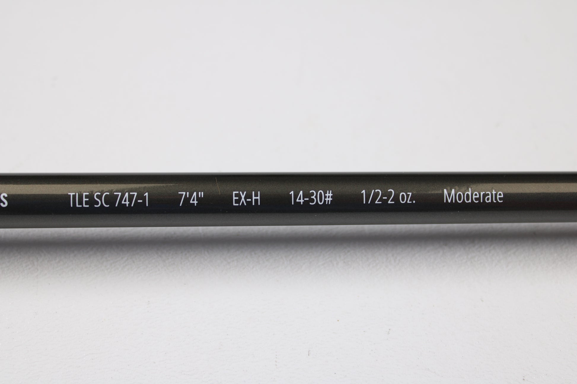 A close-up of a Temple Fork TFO Tactical Elite Bass TLE SC 747-1 7'4" Ex-Heavy used casting rod (excellent condition) shows its specs on the blank. This gear is part of our rod and reel trade-in program, displayed on a white background.