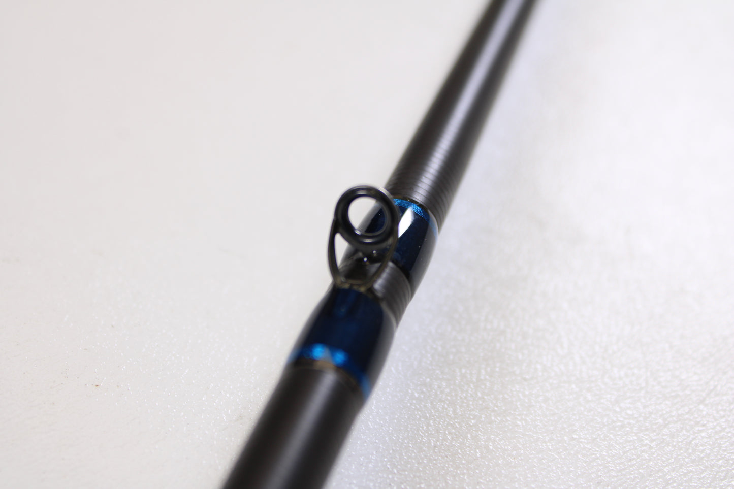 Close-up of a Kistler Helium HE703LMH 7'0" Lite Medium Heavy Used Casting Rod in excellent condition, highlighting a blue and black guide ring—ideal for quality gear seekers or those using our Rod and Reel Trade-In Program for store credit.