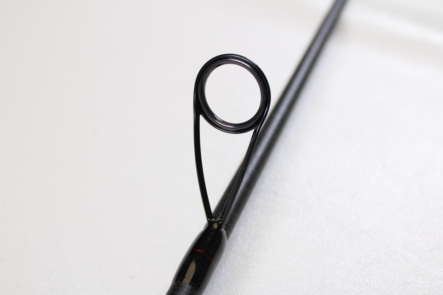 Close-up of an Ark Fishing Invoker Pro IVP71MXS 7'1" Medium used spinning rod in excellent condition, featuring a guide ring on a black rod—ideal for those seeking quality pre-owned gear.