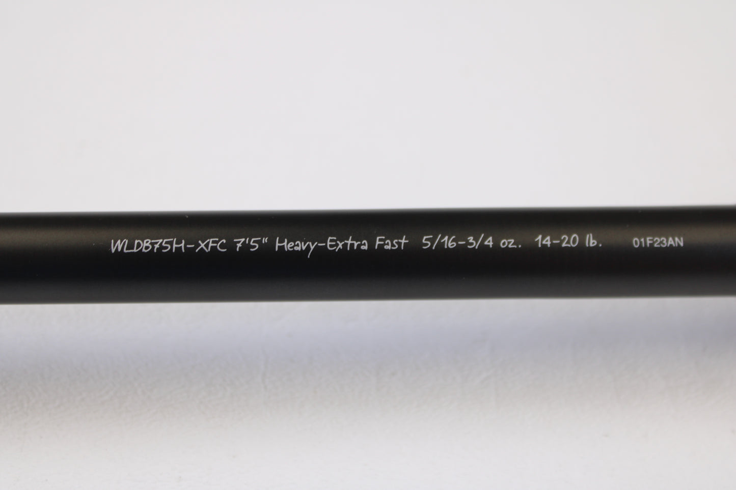 A close-up of the Fenwick World Class Bass WLDB75H-XFC 7'5" Heavy used casting rod in excellent condition, featuring white specs on a black blank, photographed against a white background and eligible for our rod and reel trade-in program.