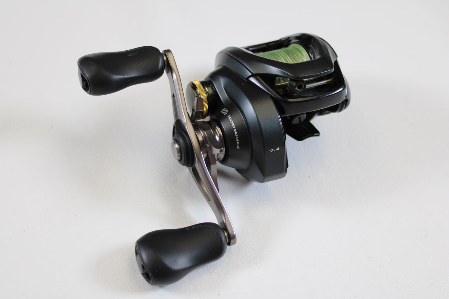 A Shimano Curado 200 K CU200HGK 7.4:1 RH used casting reel in excellent condition with dual ergonomic handles and metallic accents is displayed on a white surface—upgrade or shop quality used Shimano gear today.