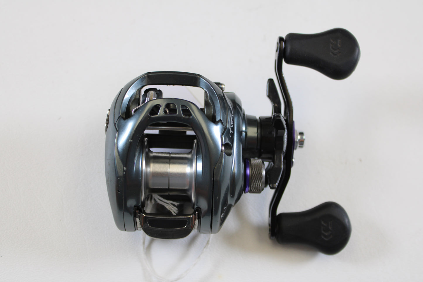 A used Daiwa Tatula SV TW TTUSV103XS 8.1:1 RH casting reel in good condition, with a metallic silver-blue finish and two black handles, ideal for our rod and reel trade-in program. Brand: Daiwa.